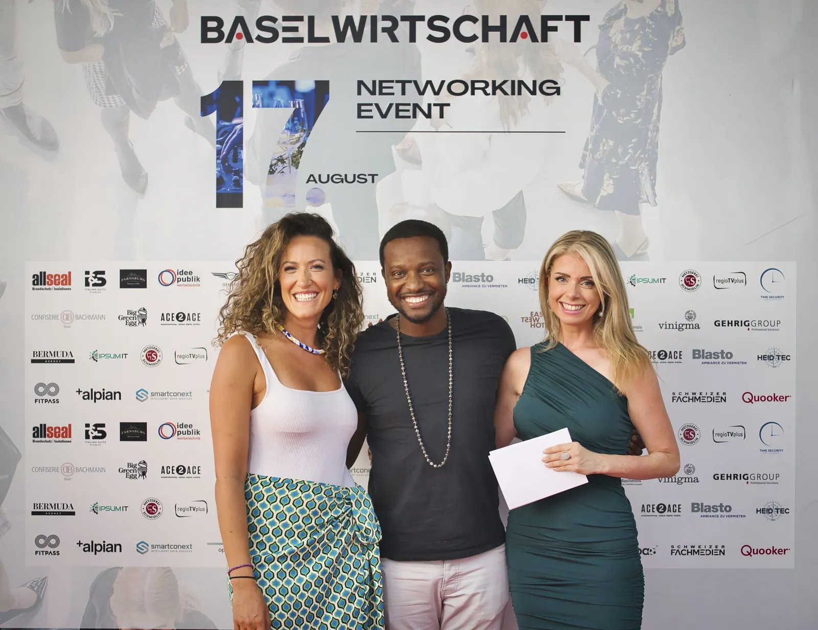 Drei Gäste vor der Fotowand mit dem Schriftzug BASELWIRTSCHAFT Networking Event